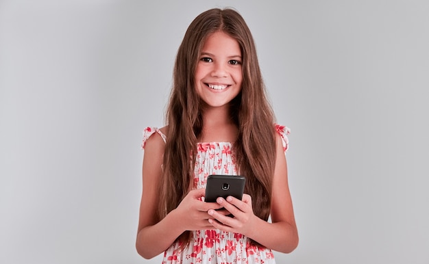 Cute girl on the gray background is using the phone