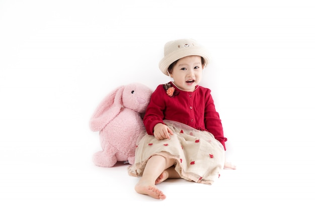 The cute girl in a hat and red dress on white