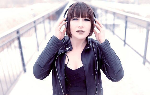 Cute girl in headphones listening to music outdoors