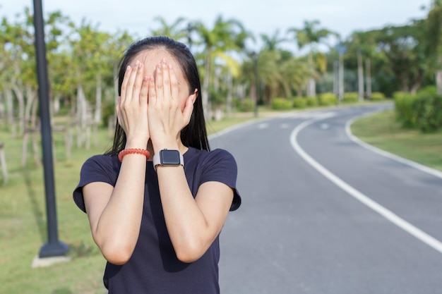 사진 귀여운 소녀는 그녀의 얼굴을 그녀의 손에 숨기고 아침에 빛을 보호합니다.