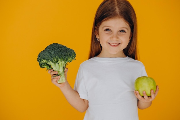 Cute girl holding broccoli and apple