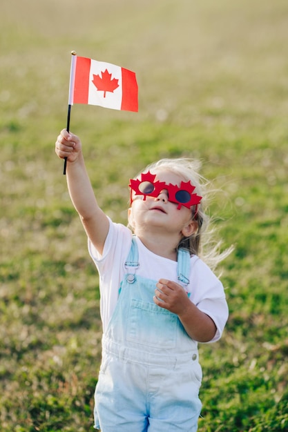 Photo cute girl holding canadian flag outdoors