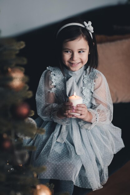 Photo cute girl holding candle sitting on chair