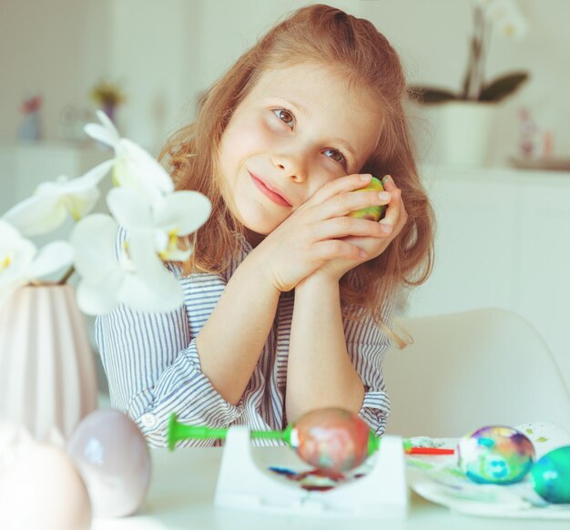 Foto ragazza carina che tiene l'uovo di pasqua mentre è seduta a casa