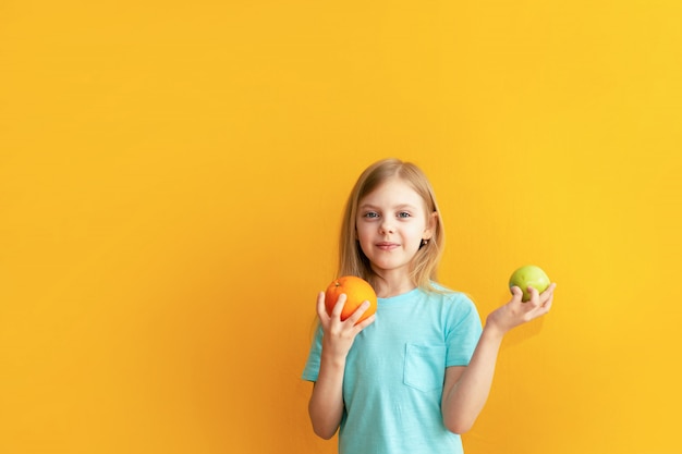 写真 オレンジ色の壁に果物を保持しているかわいい女の子