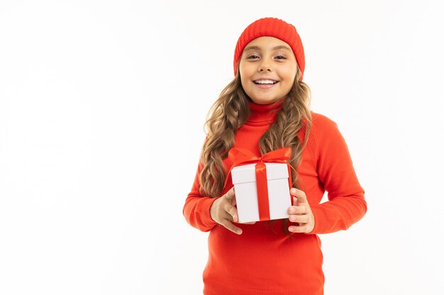 Cute girl holding a gift box on white wall