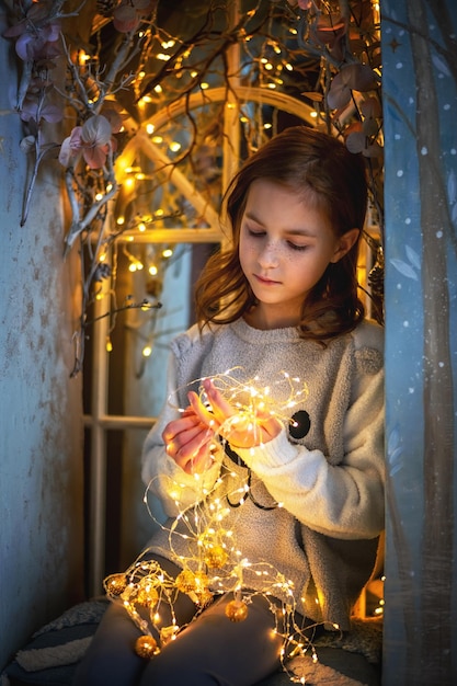 Cute girl holding a glowing garland new year christmas