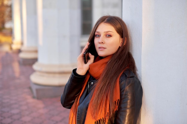 Cute girl holding phone on street Relaxed smiling woman using smart phone for calling