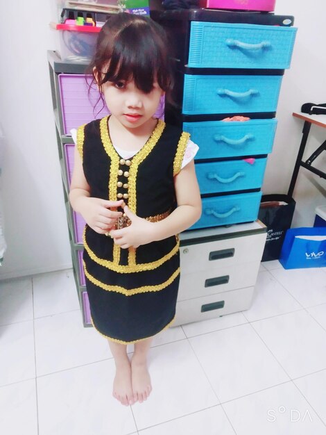 Cute girl holding umbrella while standing on tiled floor at home