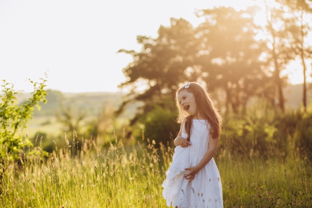 Cute girl holding white dress in green field