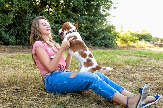 Cute girl is playing with her dog in the park