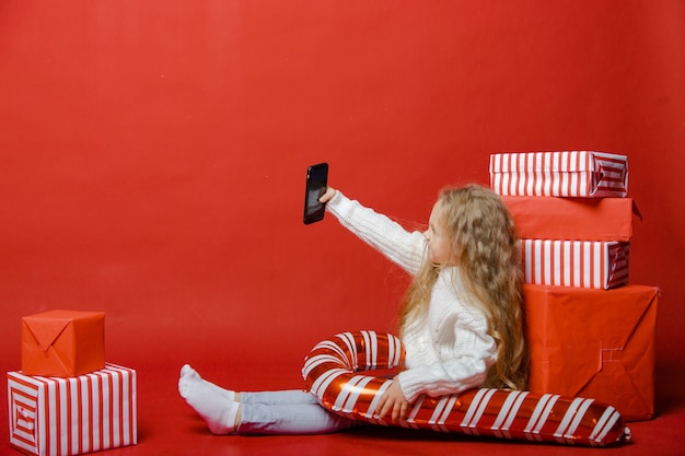 La ragazza carina si sta preparando per il nuovo anno sullo sfondo con i regali