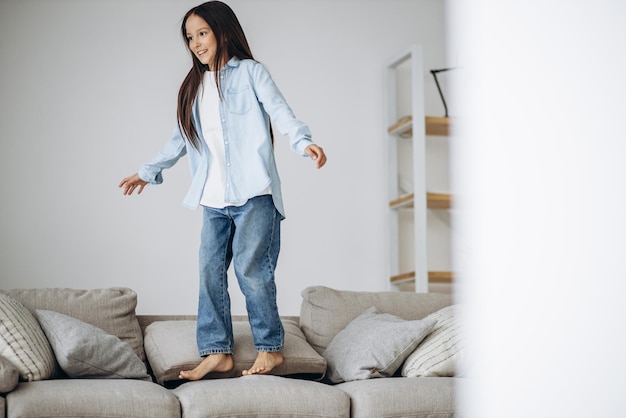 Cute girl jumping on the coach at home