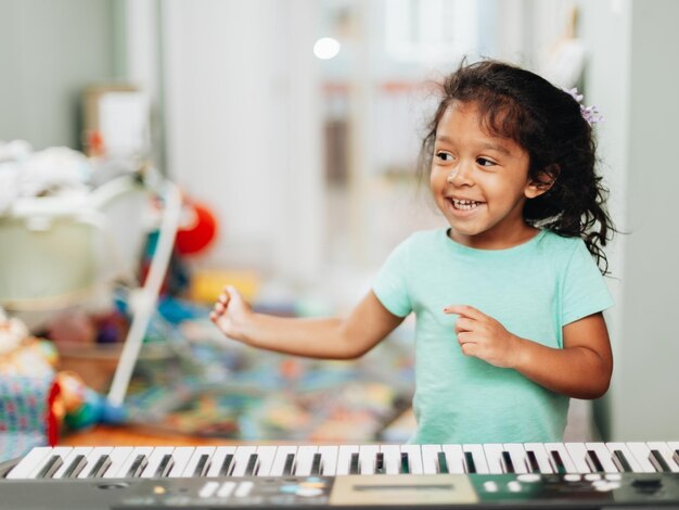 Photo cute girl learning piano at home