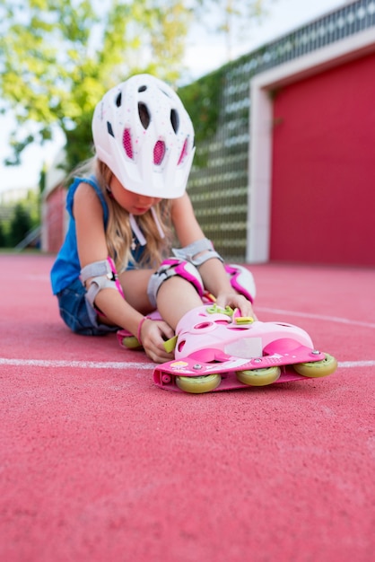 Cute girl learning to ride rollerblades on public park on sunny day