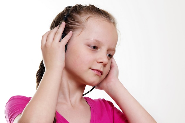 Foto ragazza carina che ascolta musica con le cuffie su uno sfondo bianco