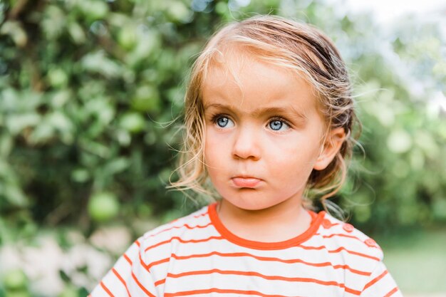 Photo cute girl looking away against trees