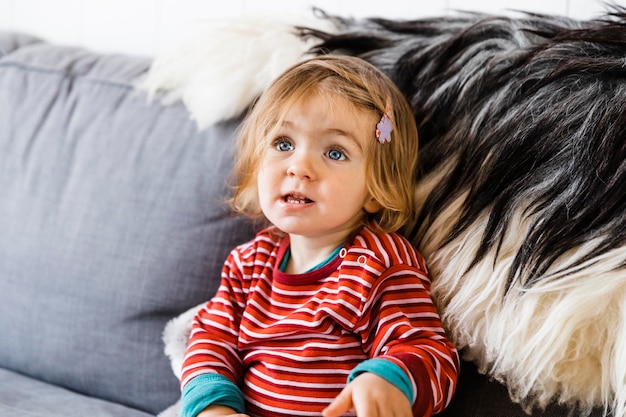 Cute girl looking away while sitting on sofa at home