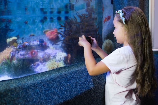 Photo cute girl looking at fish tank