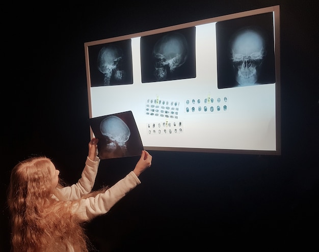 Photo cute girl looking at a picture of a human skull.