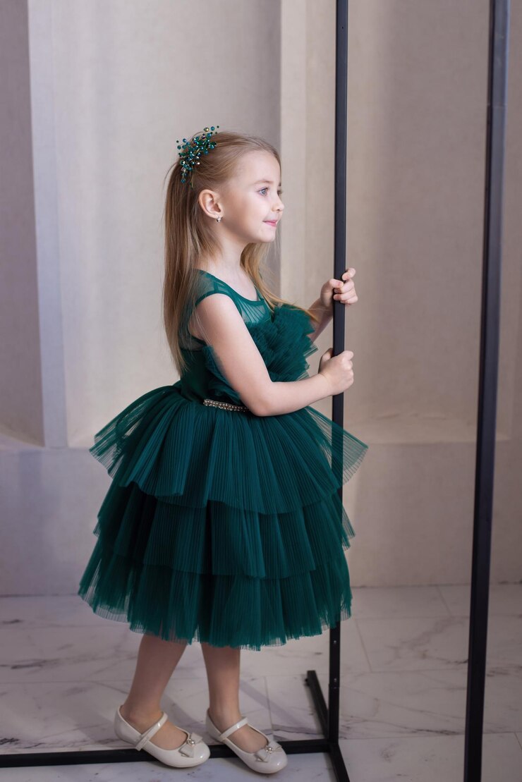 a cute girl looks out the window at a holiday in a beautiful green dress a place to copy luxury