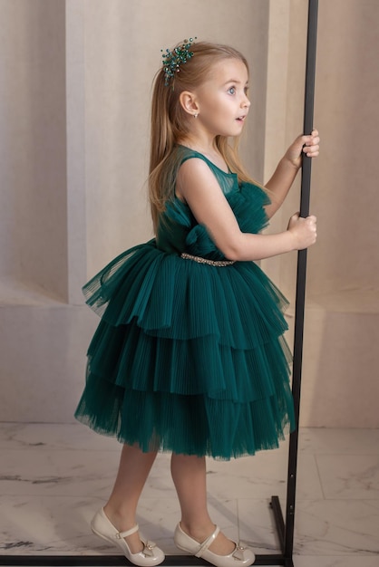 Una ragazza carina guarda fuori dalla finestra durante una vacanza in un bellissimo vestito verde, un posto dove copiare il lusso