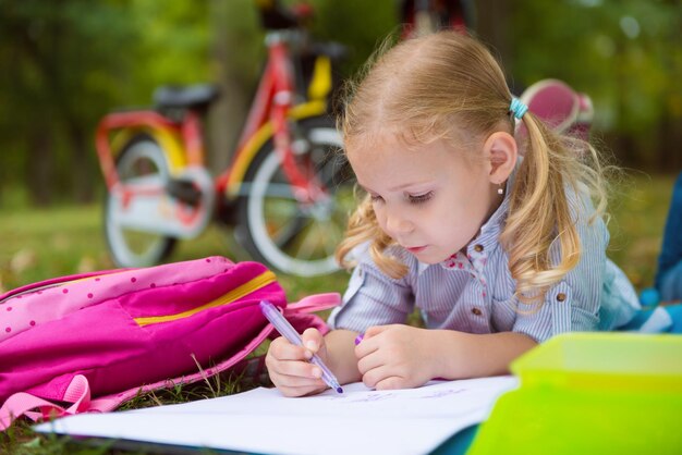 Cute girl lying on grass while writing in book outdoors