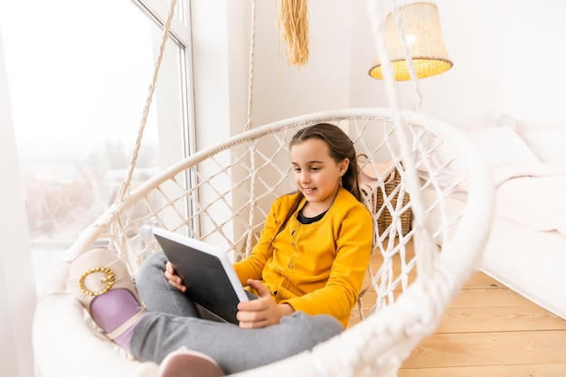 Cute girl lying on sofa with tablet computer.