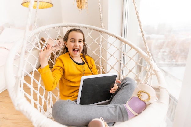 Foto ragazza carina sdraiata sul divano con computer tablet.