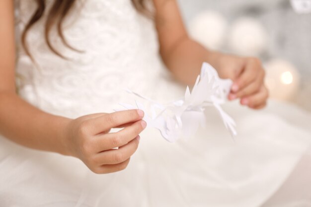 Cute girl making paper snowflakes for decorating the Christmas