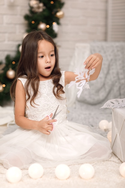 Cute girl making paper snowflakes for decorating the Christmas