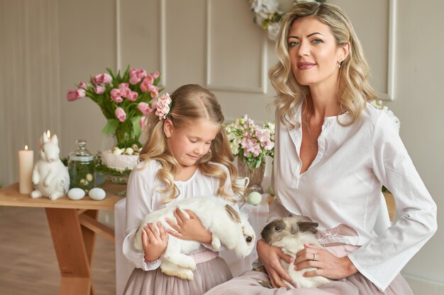 Cute girl and mother playing with rabbit