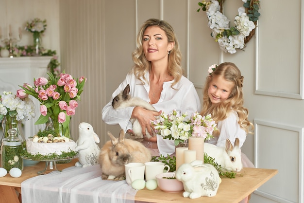 Cute girl and mother playing with rabbits