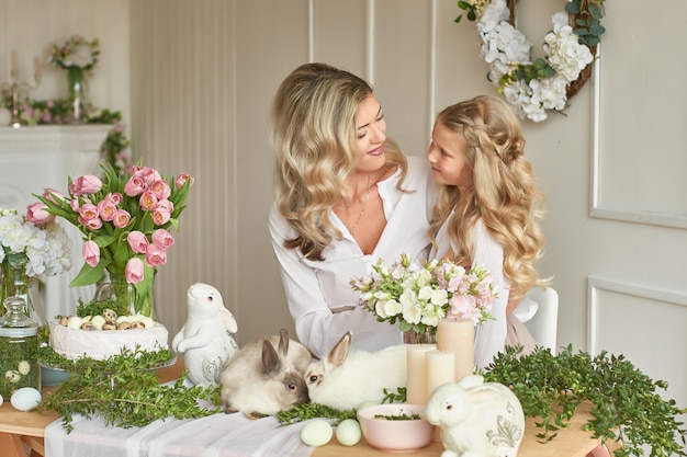 Cute girl and mother playing with rabbits