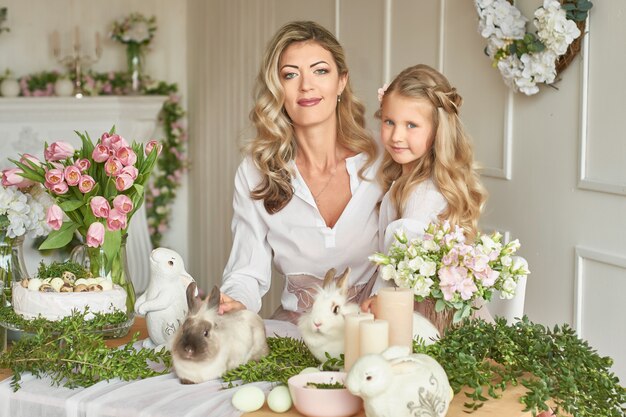 Cute girl and mother playing with rabbits