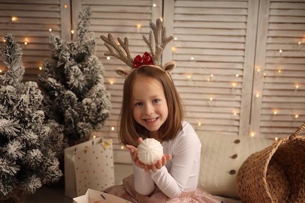 새해 의상을 입은 귀여운 소녀가 손에 크리스마스 공을 들고 있다