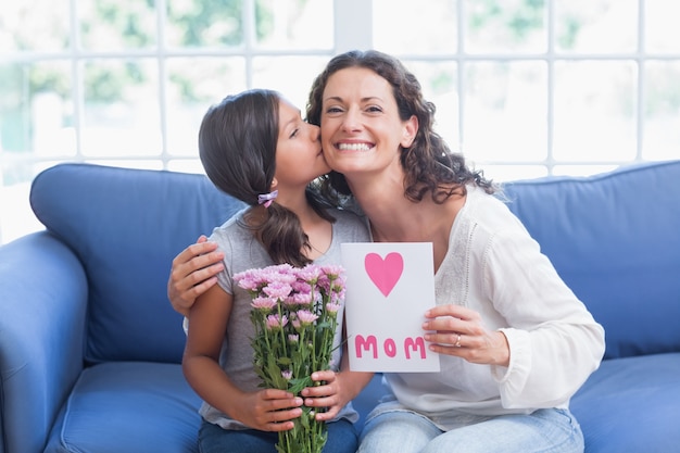 Photo cute girl offering flowers and card to her mother