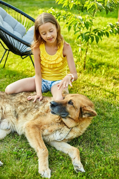 Cute girl and old dog enjoy summer day on the grass in the park