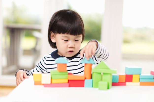 可愛い女の子がテーブルの上でおもちゃのブロックを遊んでいます