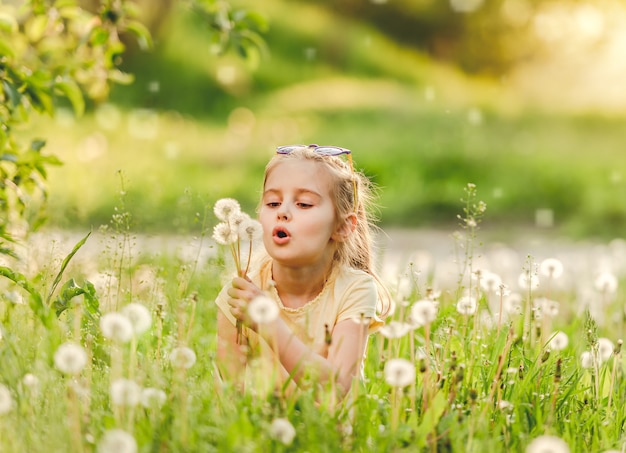 Cute girl playing with dandelions