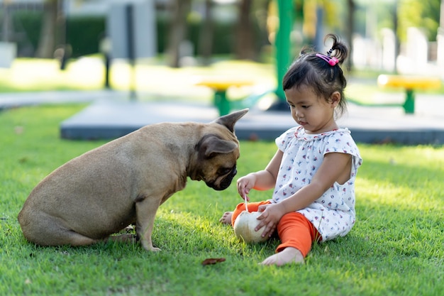 Foto ragazza carina che gioca con il cane mentre è seduta sull'erba nel parco