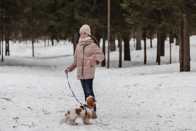 冬の公園の森で犬と遊ぶかわいい女の子