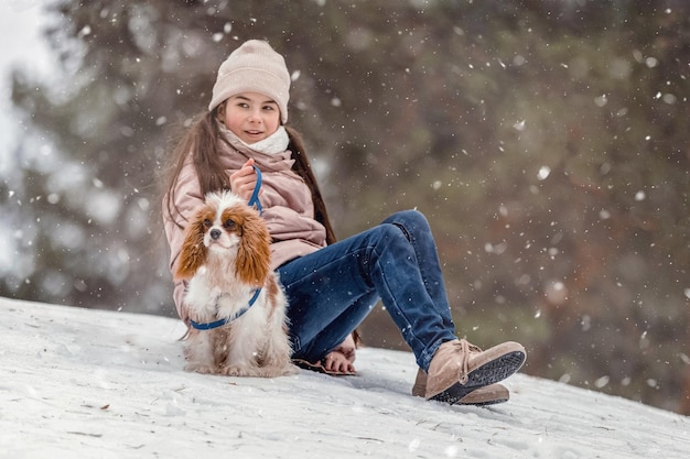 冬の公園の森で犬と遊ぶかわいい女の子