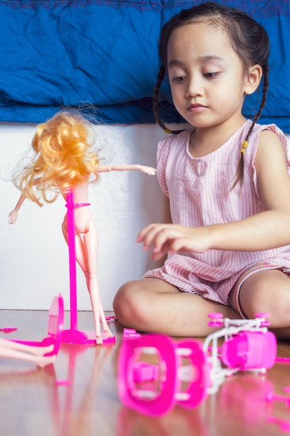 Photo cute girl playing with doll at home