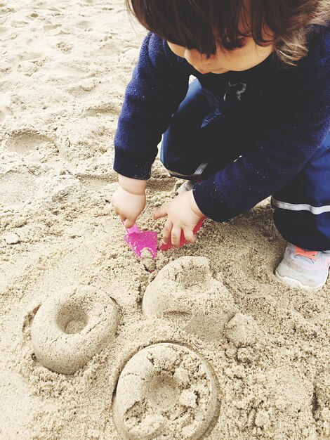 Photo cute girl playing with sand on beach