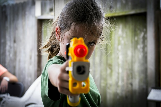 Foto una ragazza carina che gioca con una pistola a acqua all'aperto