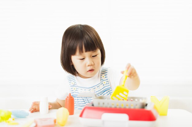 写真 テーブルの上のおもちゃで遊ぶ可愛い女の子