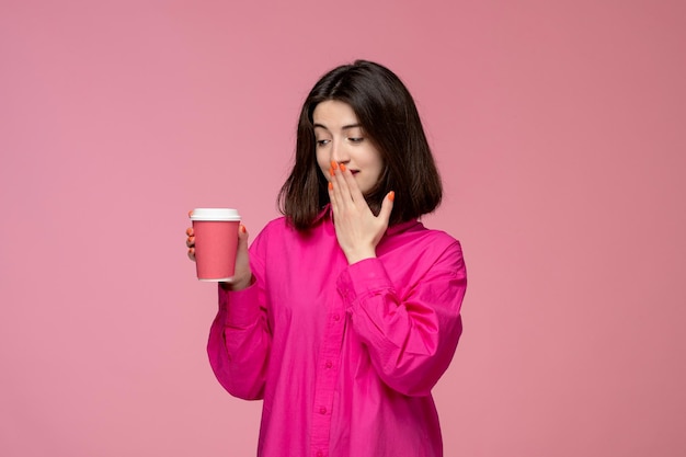 Cute girl pretty adorable girl in pink shirt with red lipstick covering mouth with pink cup