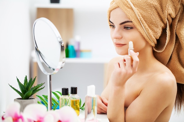 Cute girl puts makeup on the face in the bathroom