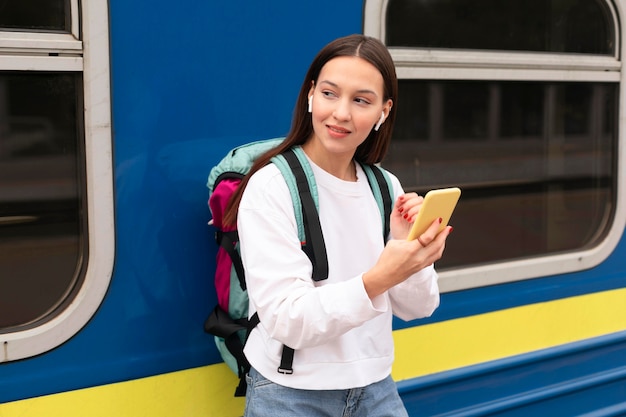 Foto ragazza carina alla stazione ferroviaria tenendo il telefono cellulare